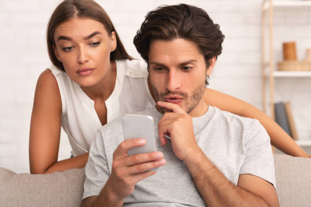 istock Girlfriend Spying On Boyfriend While He Chatting On Cellphone Indoor 1178542301