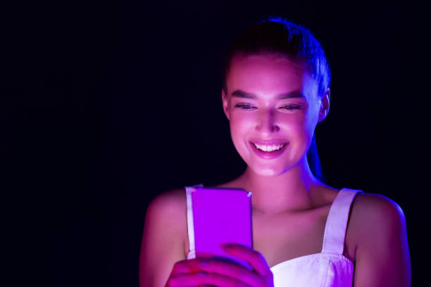 istock Happy woman using phone, illuminated by neon lights 1178543512