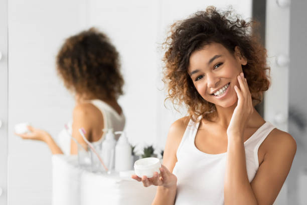 istock Afro Girl Using Face Cream Standing In Bathroom 1178544638