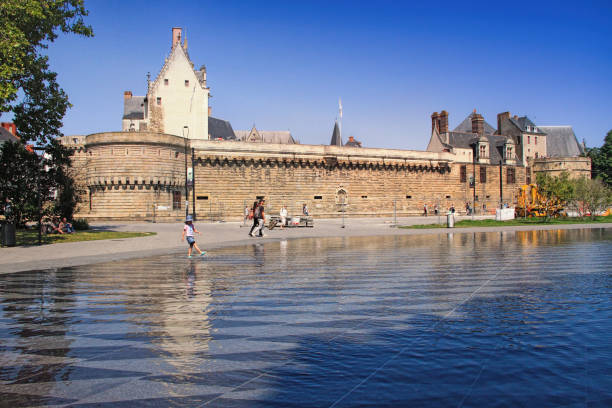 Nantes, France - August, 18, 2018 : View on the castle of Dukes of Brittany with water mirror fountain and tourists in Nantes city in France