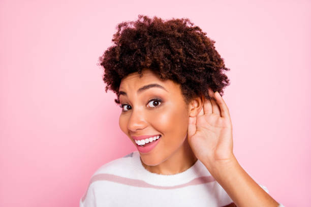 Close up photo of curly trendy cute sweet charming darkish skinned lady smiling toothily eavesdropping talks with cheerful unexpected facial expression isolated pink pastel color background Close up photo of curly trendy cute sweet charming darkish skinned, lady smiling toothily eavesdropping talks with cheerful unexpected facial expression isolated pink pastel color background eavesdropping stock pictures, royalty-free photos & images