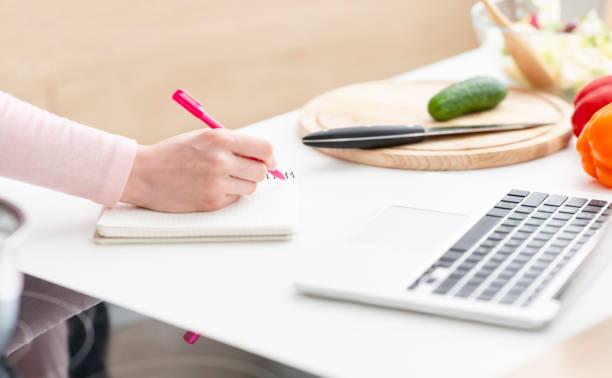 istock Woman writing down thoughts in copybook and working on laptop 1178546750