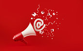 At Symbol Coming Out of  A Megaphone with Gift Boxes Paper Confetti and Party Streamers Falling on Red Background