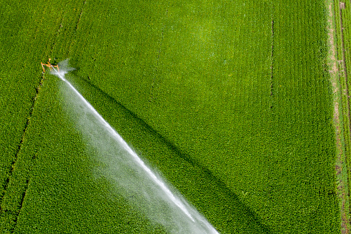Top view aerial shot of irrigation sprayer irrigating cultivated fields on countryside
