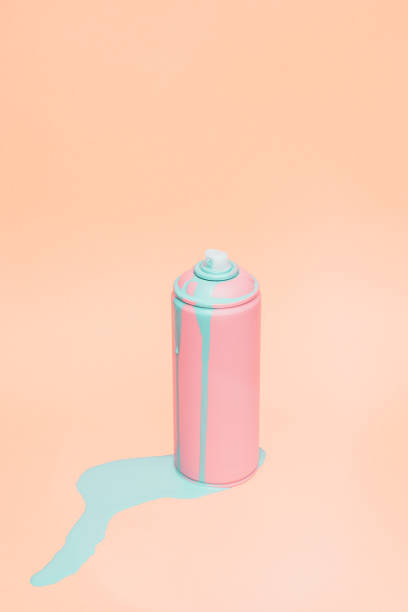 Clean still life picture of pink spray can. There blue paint flowing out of it. Taken on pink background.