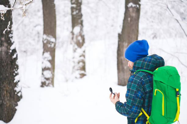 человек ищет направление с компасом в зимнем снежном лесу - orienteering planning mountain climbing compass стоковые фото и изображения