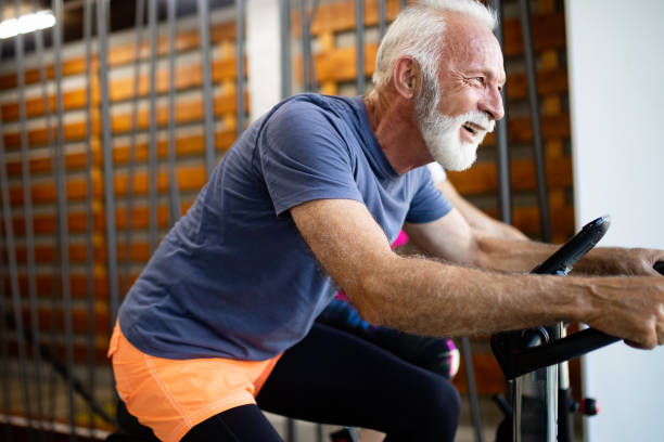 dojrzałe dopasowanie ludzi na rowerze w siłowni, ćwiczenia nogi robi cardio treningu rowerowych rowerów - spinning gym cycle cycling zdjęcia i obrazy z banku zdjęć