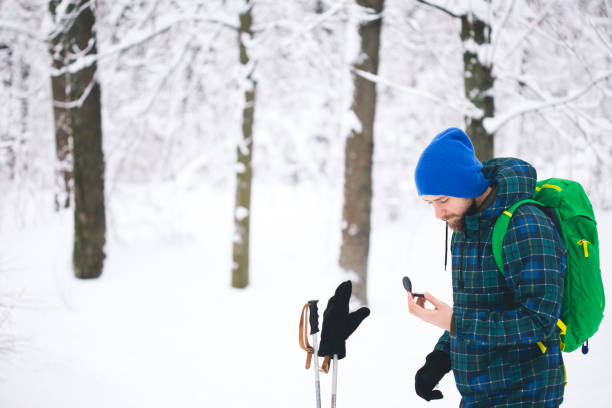 mann suche richtung mit kompass im verschneiten winterwald - orienteering planning mountain climbing compass stock-fotos und bilder