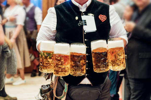 waiter carrying beer glasses at Octoberfest in Munich waiter carrying a lot of beer glasses in beer garden at Octoberfest in Munich munich stock pictures, royalty-free photos & images