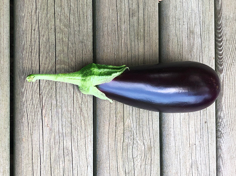 Single eggplant on a wooden background.