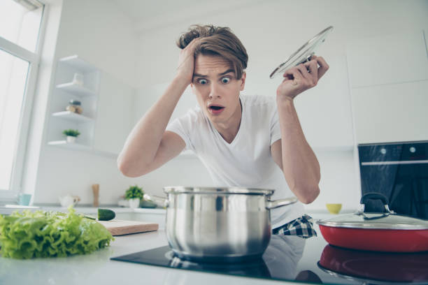 Close-up portrait of his he nice attractive overwhelmed clueless puzzled guy making dinner lunch looking at boiling bouillon at light white modern style interior house indoors Close-up portrait of his he nice attractive overwhelmed clueless puzzled guy making dinner, lunch looking at boiling bouillon at light white modern style interior house indoors ugly soup stock pictures, royalty-free photos & images