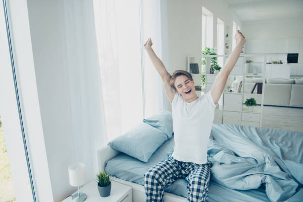 portrait of positive cheerful man wake up yawn stretch hands feel satisfied have wonderful holidays weekends wear checkered plaid sleep-wear in house indoors - material data sheets imagens e fotografias de stock