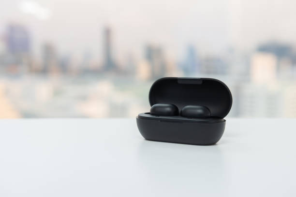 istock True wireless earbuds in battery case on the white table with blur city scape background 1178563112