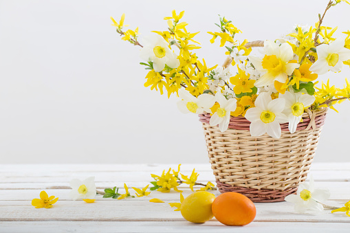 Easter eggs with spring flowers on white wooden table
