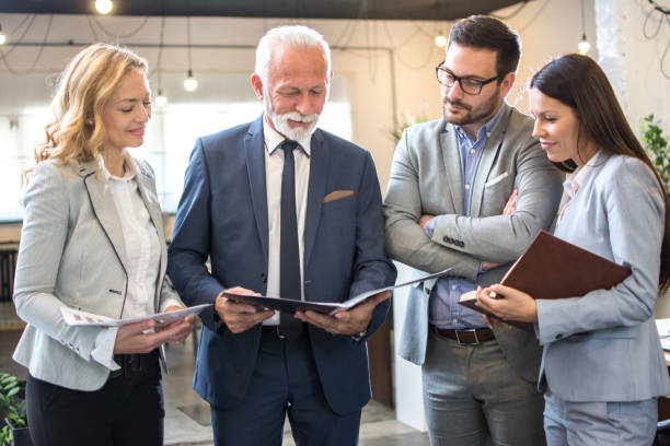 istock Group of multi-aged business people analyzing paper documents together in office 1178565907