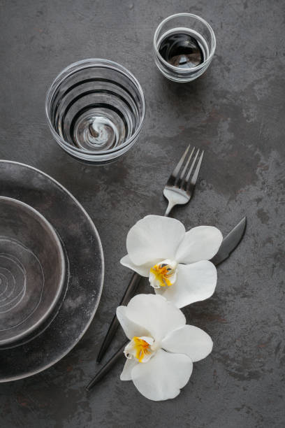 istock Elegance table setting with knitted grey napkin, cutlery, ceramic plates, glasses and white orchid flowers 1178568570