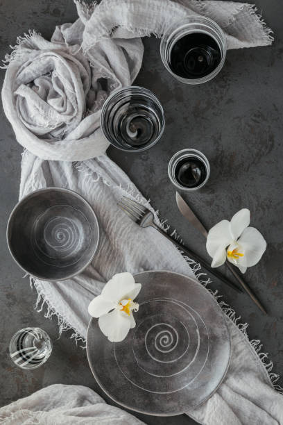 istock Elegance table setting with knitted grey napkin, cutlery, ceramic plates, glasses and white orchid flowers 1178568574