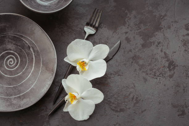 istock Elegance table setting with knitted grey napkin, cutlery, ceramic plates, glasses and white orchid flowers 1178568575