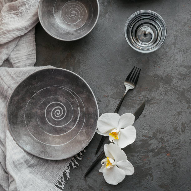 istock Elegance table setting with knitted grey napkin, cutlery, ceramic plates, glasses and white orchid flowers 1178568582