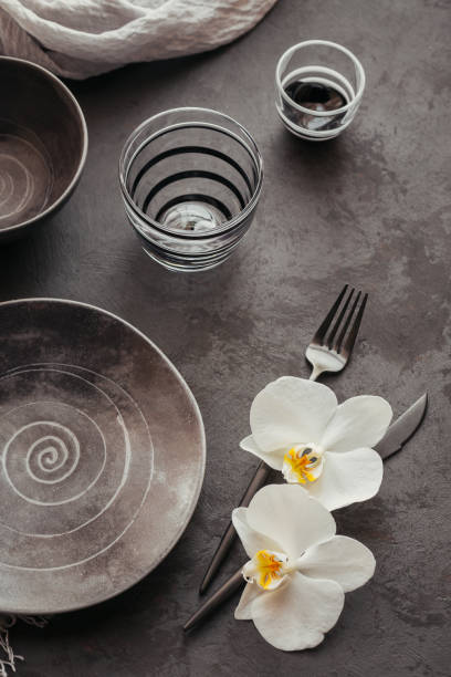 istock Elegance table setting with knitted grey napkin, cutlery, ceramic plates, glasses and white orchid flowers 1178569014