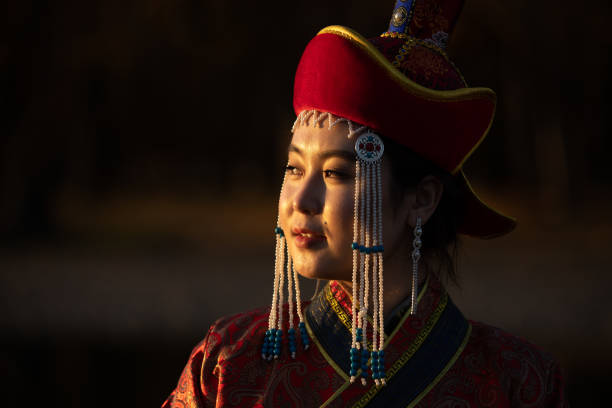 Portrait of a young woman in traditional Mongolian dress. Beautiful young woman posing in traditional Mongolian dress in sunset light. Ulaanbaatar, Mongolia. independent mongolia stock pictures, royalty-free photos & images