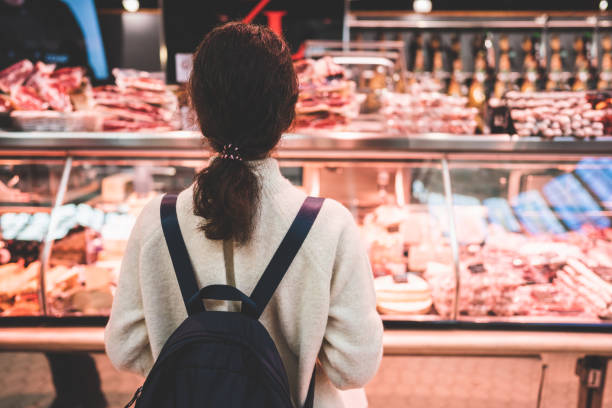 donna che sceglie la carne allo stand del macellaio - meat supermarket butchers shop market foto e immagini stock