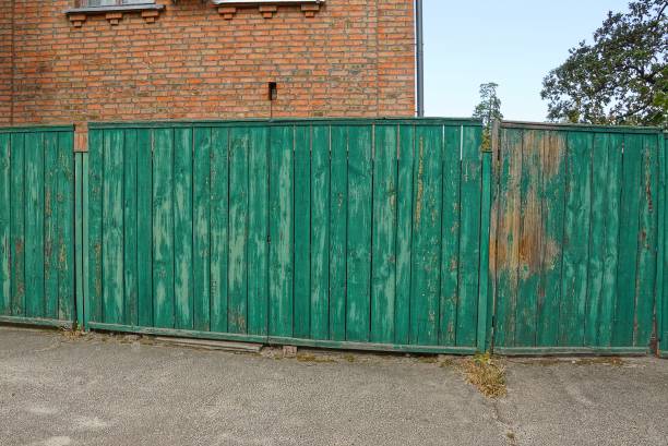 istock old long green gate on the street 1178573573