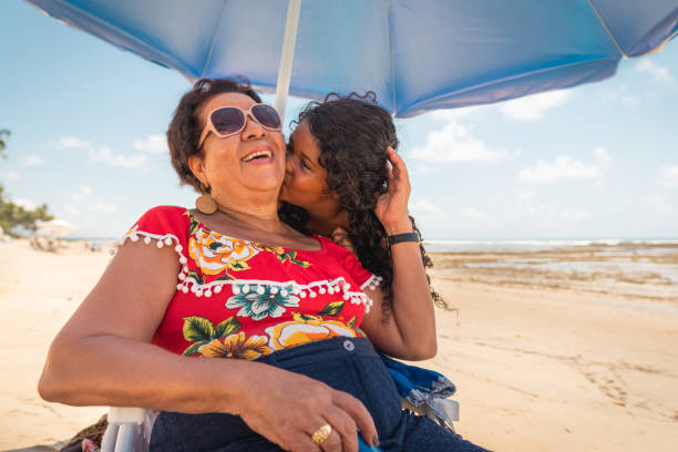 Girl kissing grandma and enjoying the tropical beach Two Generation Family, Family, Females, Beach, Holiday latin american and hispanic culture photos stock pictures, royalty-free photos & images