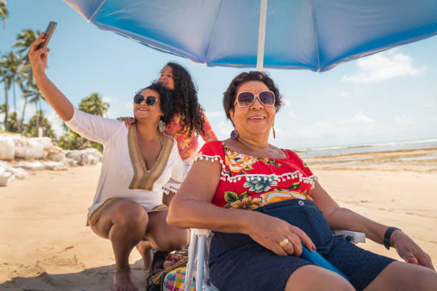 famille apprécient le week-end sur la plage - wireless technology cheerful granddaughter grandmother photos et images de collection