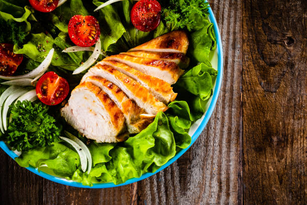 istock Caesar salad  - vegetable salad with roast chicken meat on wooden background 1178577836