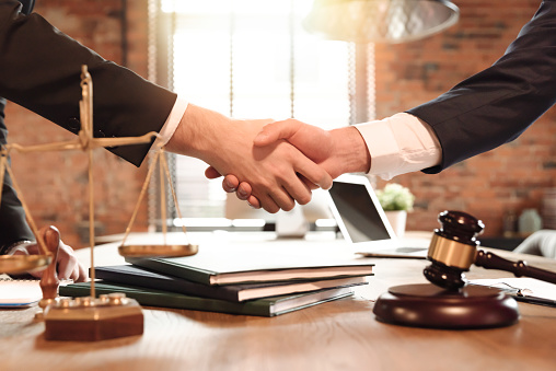 Lawyer and his client handshake. Agreement with attorney in office. Law and justice concept