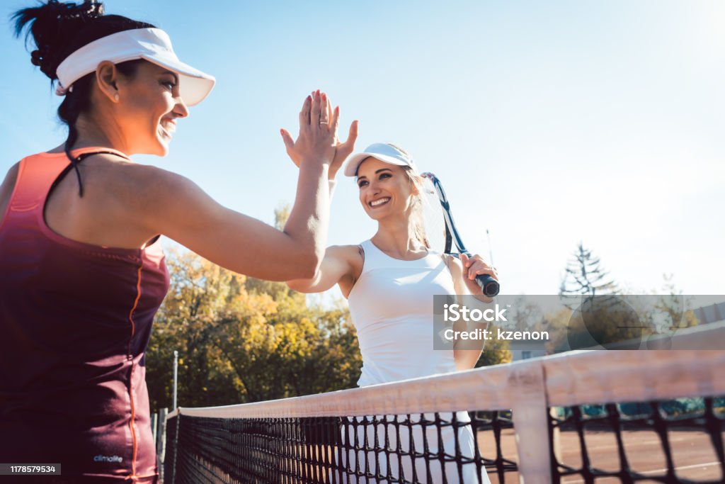 Women giving high five after a good match of tennis Women giving high five after a good and friendly match of tennis Tennis Stock Photo