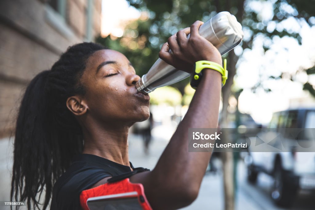 Afro american woman with dreadlocks in a great athletic shape working out and training hard outdoors Water Bottle Stock Photo
