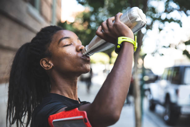 afro american woman with dreadlocks in a great athletic shape working out and training hard outdoors - water bottle water bottle drinking imagens e fotografias de stock