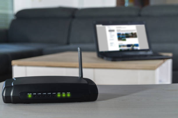 Home internet router on desk. Home internet connection. A wlan router on desk with notbook in background. bandwidth stock pictures, royalty-free photos & images