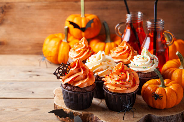 Halloween cupcakes and pumpkins on wooden background. Sweets for holiday party. Halloween cupcakes and pumpkins on rustic wooden background. Sweets for holiday party. halloween cupcake stock pictures, royalty-free photos & images