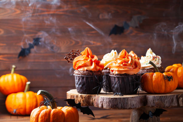 Halloween cupcakes and pumpkins with spiders and smoke on dark background. Sweets for holiday party. Halloween cupcakes and pumpkins with spiders, bats and smoke on dark background. Sweets for holiday party. halloween cupcake stock pictures, royalty-free photos & images