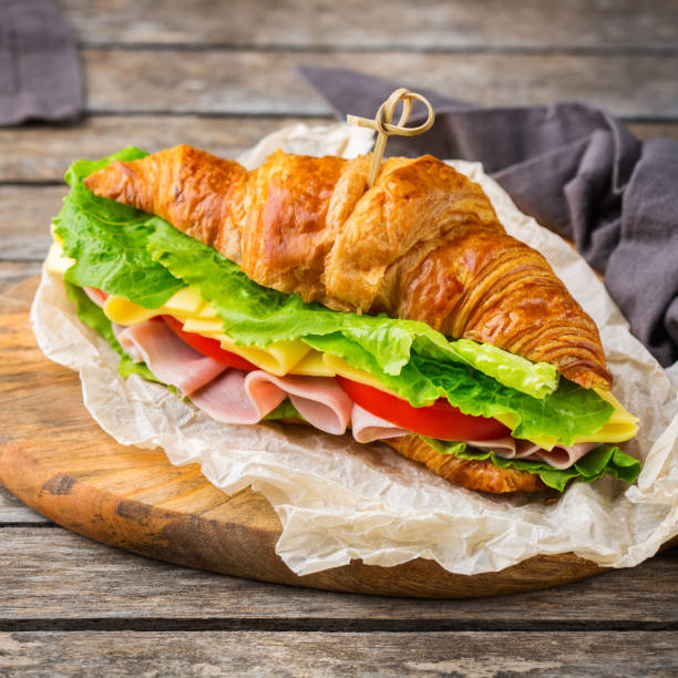 istock Fresh croissant sandwich with ham, cheese, lettuce and tomato 1178590292