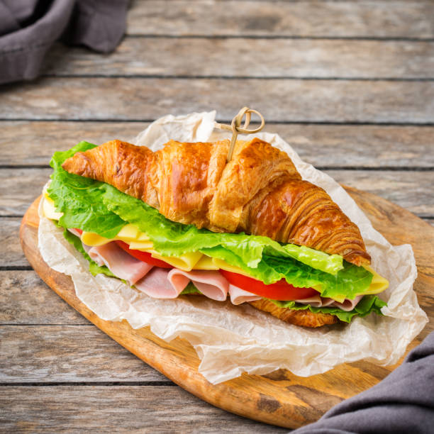 panino al croissant fresco con prosciutto, formaggio, lattuga e pomodoro - morning tomato lettuce vegetable foto e immagini stock