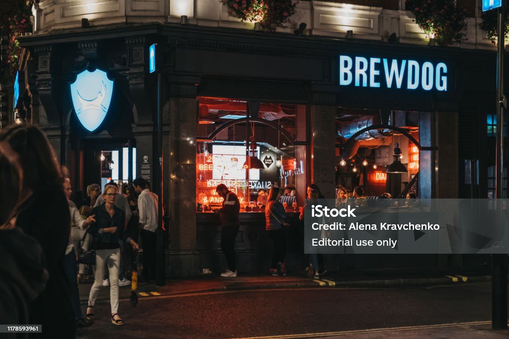 People standing outside Brewdog pub in Covent Garden, London, UK. London, UK - August 31, 2019: People standing outside Brewdog pub in Covent Garden, one of the most popular tourist sites in London, UK. In the evening, selective focus. Night Stock Photo