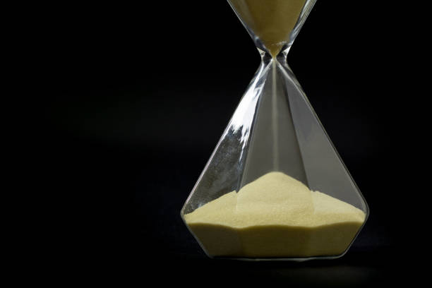 istock golden sand in hourglass isolate on black background. 1178594590