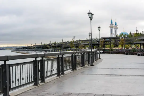 Photo of Kremlin Embankment in Kazan in cloudy day. The embankment Kazanka River. Smooth asphalt, bicycle lines, roller-skate, walking, pedestrian paths.