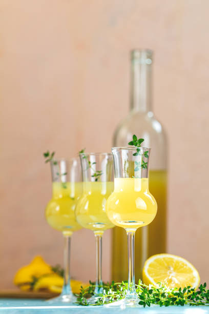 istock Limoncello with thyme in grappas wineglass with water drops on light concrete table. Artistic still life on light background with sunny light 1178604620