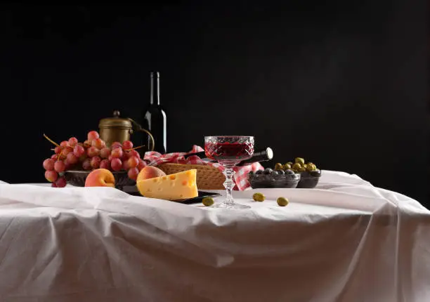 Photo of Panorama with a glass of wine, olives, cheese and grapes on a dark background