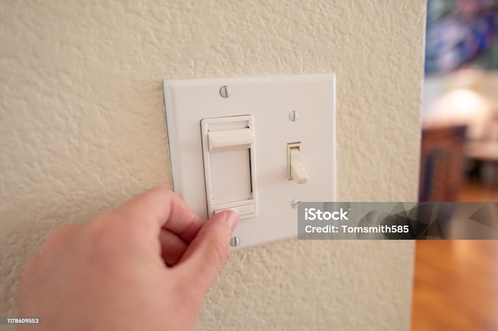 POV Man Adjusting Dimmer Switch Close-up, personal perspective or point of view of human hand of a man adjusting dimmer switch on wall light switch, September 24, 2019 Dimmer Switch Stock Photo