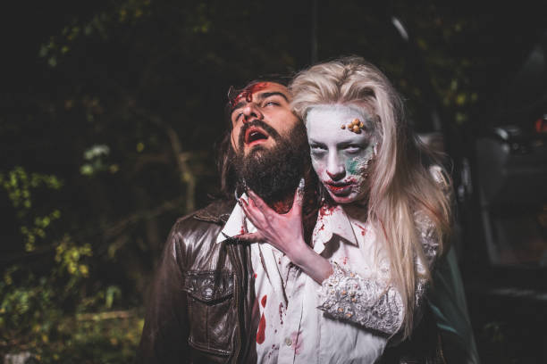 Zombie biting man Woman dressed as witch biting man at night. Zombie concept male vampire biting his victim stock pictures, royalty-free photos & images