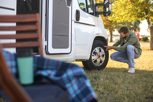 Man checking a tire on a recreational vehicle. About 30 years old Caucasian male.