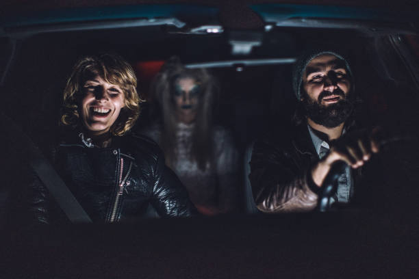 Halloween Young couple sitting in car with a scary witch/ghost/demon/monster/zombie behind them couple driving at night stock pictures, royalty-free photos & images
