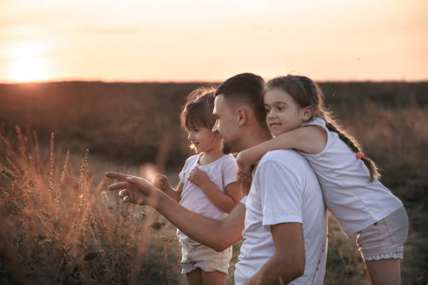 istock Dad and his daughters in the field at sunset . 1178618685