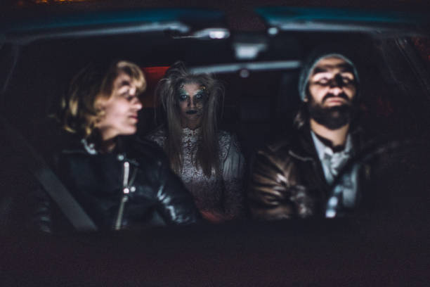 Halloween Young couple sitting in car with a scary witch/ghost/demon/monster/zombie behind them couple driving at night stock pictures, royalty-free photos & images